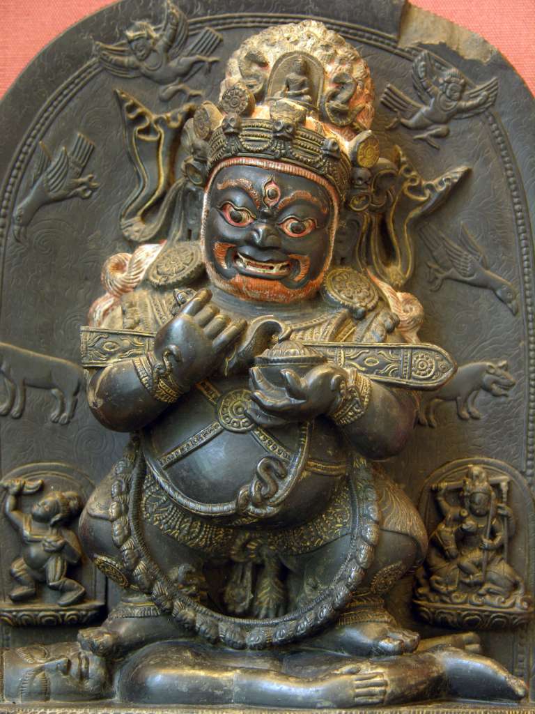 British Museum Top 20 Buddhism 13 Mahakala 13. Mahakala � Tibet, 17C AD. This stone stele shows the dharmapala (protective figure) Mahakala as Lord of the Tent, an appropriate role given the nomadic lifestyle of many Tibetans. The garland of skulls, his fierce expression and the prone male figure being trampled underfoot all add to his terrifying appearance. These symbolize his ability to destroy all impediments to enlightenment. Mahakala holds in the crooks of his arms the long wooden sounding board used to summon monks to assembly.  The half-bird, half-man figure of the Hindu deity Garuda is shown alongside Mahakala. In Mahakala's head-dress is his parent Buddha, Akshobhya, the Tathagata Meditation Buddha of the East.